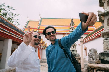 Men in a Buddhist temple take selfies on the phone.