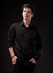 Smiling handsome man in black shirt posing on a black background