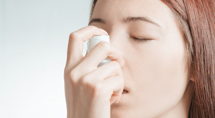 Portrait of woman using medical asthma inhaler.