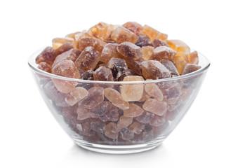 Glass bowl of natural brown caramelized sugar cubes on white background.
