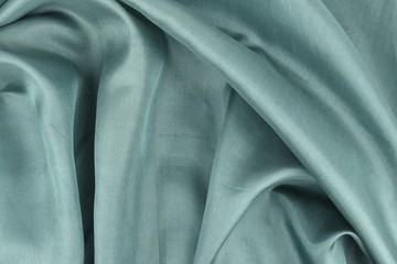 Gray green natural silk is draped with soft pleats, background