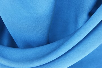Natural silk of azur blue color is draped with soft pleats, background