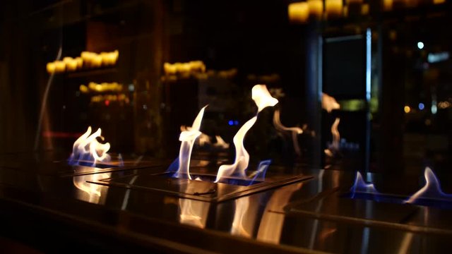 A slow motion shot of three controlled open flames outside a restaurant to appeal to the higher class and the wealthy 