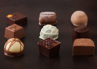 Luxury Chocolate candies selection on brown table background.White, dark and milk chocolate assortment.