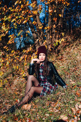 Fototapeta na wymiar Beautiful elegant woman sitting in a park in autumn
