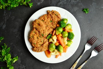 Chicken breast and vegetables. Grilled, baked chicken breast with carrots, brussels sprouts and broccoli. Meat in a white plate on a dark background isolated.
