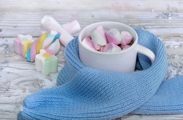 mug full of marshmallows on a blue child  scarf on a table