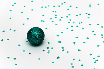 Christmas minimal composition. Turquoise glittering Christmas ball on a white background adorned with turquoise stars. Christmas, winter, New year concept. Festive background. Copy space