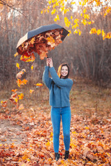 Girl makes rain from the leaves in autumn park