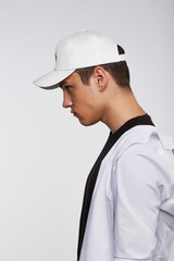 Cropped side photo of a dark-haired man, wearing white baseball cap with lettering 