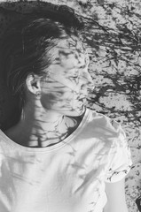 Black and white shot of Headshot portrait of female looking away with floral shadow on her face