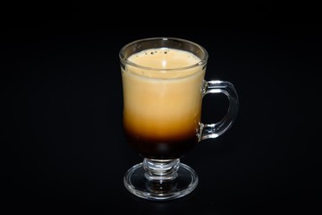 Very creamy espresso shot mug on black background 