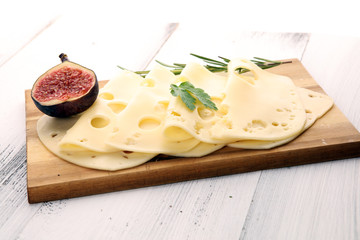 cheese slices on wooden tray with parsley. gauda cheese
