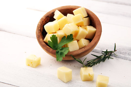 cheese cubes in wooden bowl with parsley. cheese pieces on table