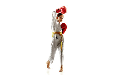 Confident junior in kimono practicing hand-to-hand combat, martial arts. Young female fighter with yellow belt s training on white studio background. Concept of healthy lifestyle, sport, action.