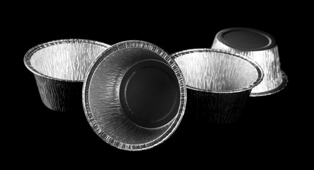 Disposable aluminum bowls, plates isolated on black background