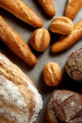 Fresh pastries. French baguettes, buns, rye and wheat bread on astone stone surface. Top view.