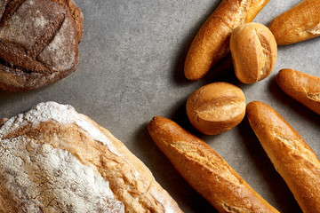 Fresh pastries. Baguettes, buns, rye and wheat bread on a gray stone surface. Top view.