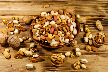 Mixed nuts on wooden table. Walnuts, pistachio, almond, peanut, cashew, hazelnut in ceramic bowl. Healthy eating concept