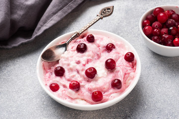 Cottage cheese dessert of yogurt jam and cranberries on a plate. grey concrete table. Concept healthy useful Breakfast. Copy space.