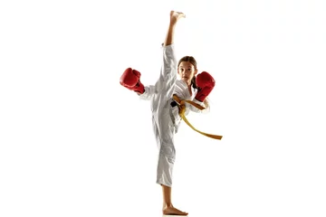 Fotobehang Confident junior in kimono practicing hand-to-hand combat, martial arts. Young female fighter with yellow belt s training on white studio background. Concept of healthy lifestyle, sport, action. © master1305