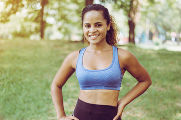 Fototapeta premium Portrait of black curly hair woman standing and resting after break workout at park,Happy and smiling,Relaxing time
