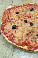 pizza with ham and mozzarella on a wooden table