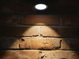 The brick wall is lit by a lamp. Close-up. Brick wall for background. Brick backlight.