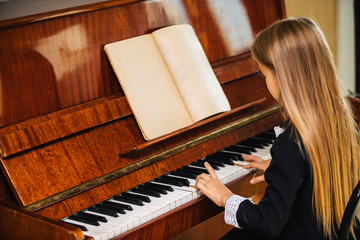 Little girl in a black dress learns to play the piano. The child plays a musical instrument.