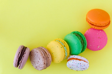Sweet colorful French macaroon biscuits on pastel yellow background