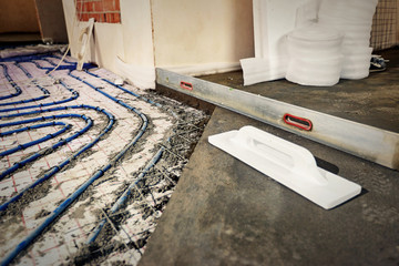 Laying blue pipes for floor heating at the construction site.