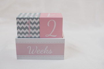 Rosa grauer Wochenwürfel 12 Wochen 12 weeks vor weißem Hintergrund