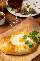 Adjarian khachapuri with egg yolk and cheese isolated on a set wooden table