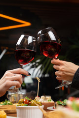 Clinking glasses of red wine above the table full of meals