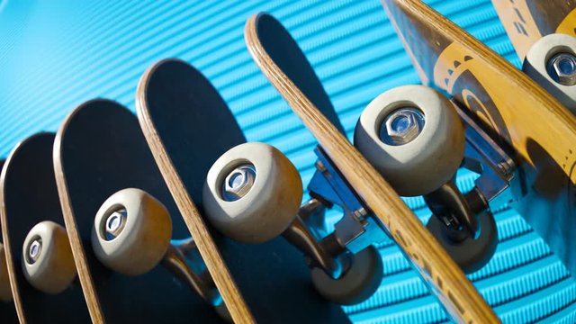 An endless row of standing skateboards with a blue wall in the background. 4KHD