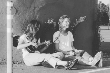 Black and white shot of Young women playing ukulele and sing song on the street