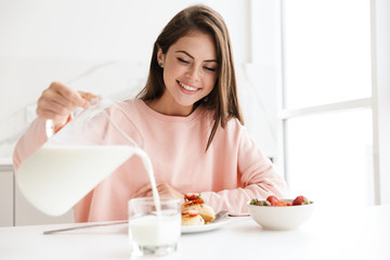 Obraz na płótnie Canvas Beautiful smiling young girl having tasty healthy breakfast