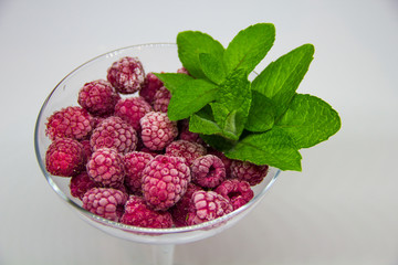 frozen raspberries with mint leaves on a white background