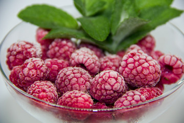 frozen raspberries with mint leaves on a white background