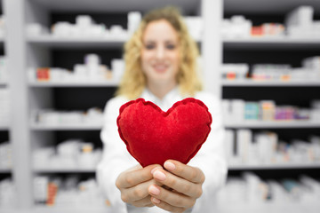 Heart medicines for cardiovascular problems. Pharmacist in drug store holding heart. In background...