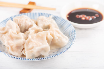 Fresh, delicious boiled pork, shrimp gyoza dumplings on white background with soy sauce and chopsticks, close up, lifestyle. Homemade design concept.