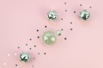 Holiday Christmas flat lay with glass transparent balls with silver sparkle on a pink background
