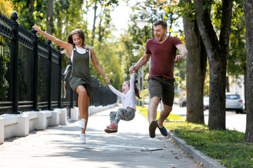 Young family with daughter have fun and run outside in the park.