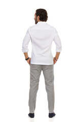 Rear View Of Standing Elegant Man In Gray Trousers And White Shirt.