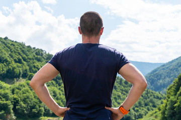 Fototapeta premium Adult man standing back to camera and looking on mountains