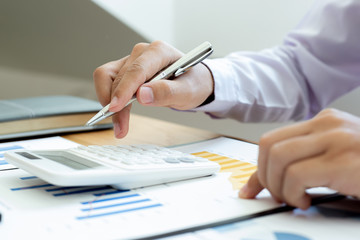 Calculate the calculator, Male employees work in private rooms Calculating company revenue figures with calculator, Financial accounting concepts