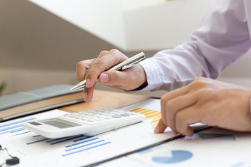 Fototapeta premium Calculate the calculator, Male employees work in private rooms Calculating company revenue figures with calculator, Financial accounting concepts