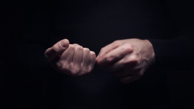 A man makes an obscene gesture showing the middle finger, close-up on a black background