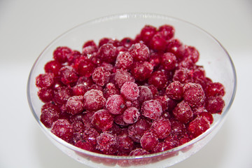 frozen red currants in a glass plate on a white background
