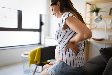 Beautiful pregnant woman expecting baby feeling tired with back pain